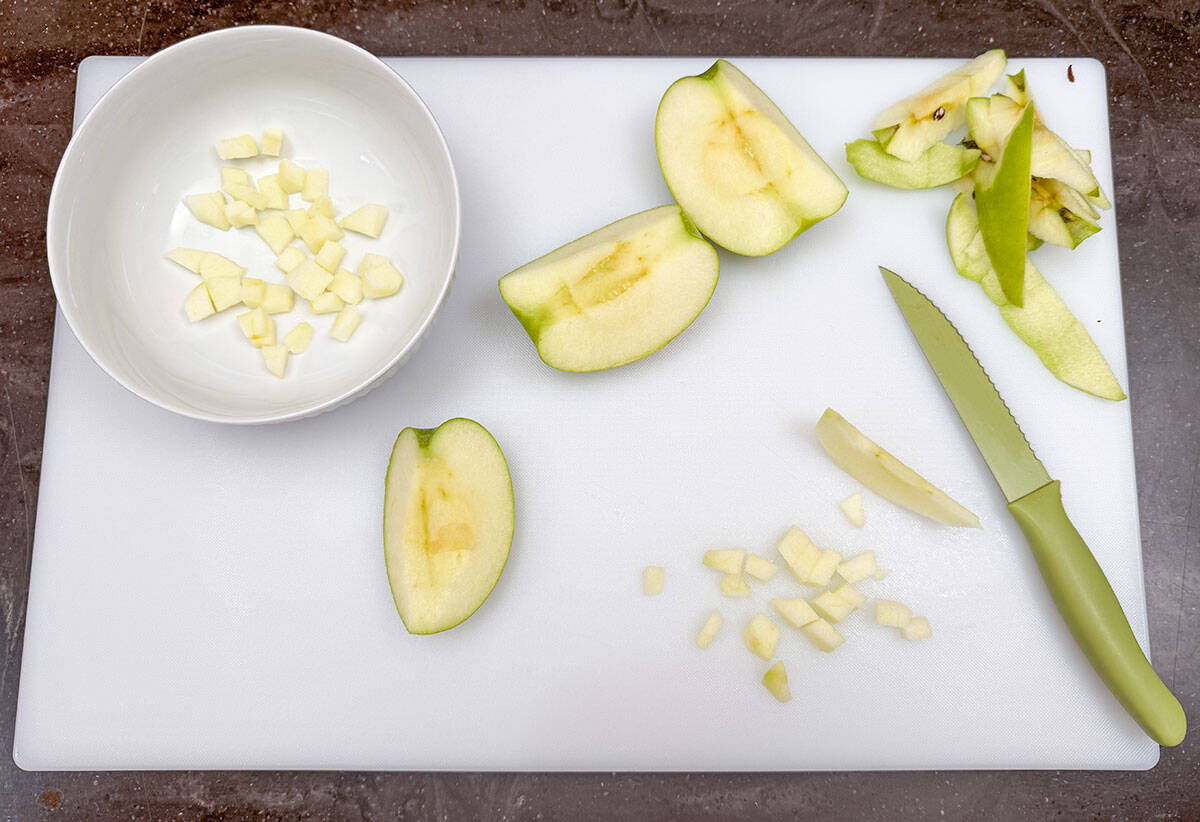 Peeled and diced granny smith apple on a cutting board.