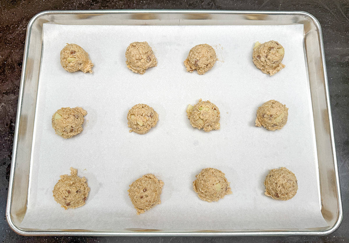Scooped apple caramel oatmeal cookies on parchment-lined sheet pan.
