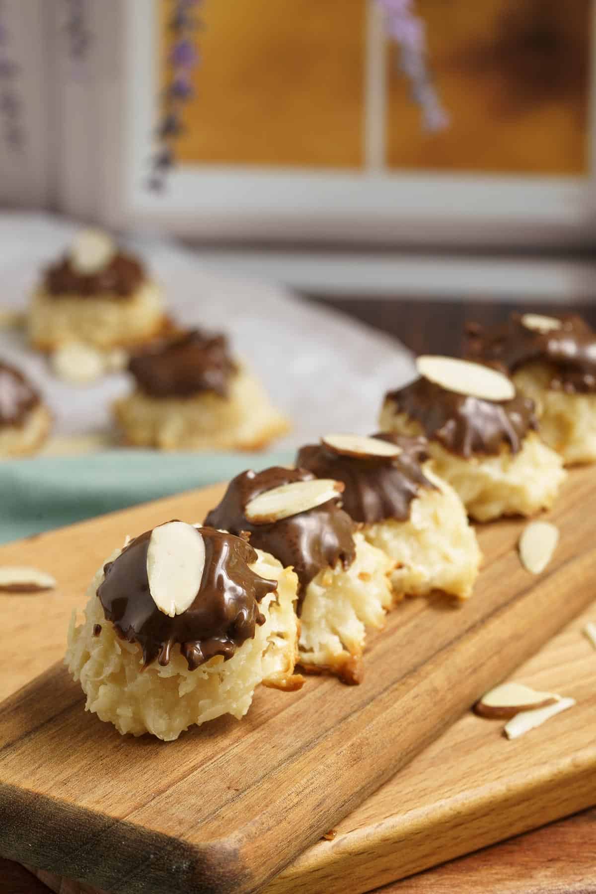 Easy creamy Coconut macaroons on a wooden plank in front of a window.