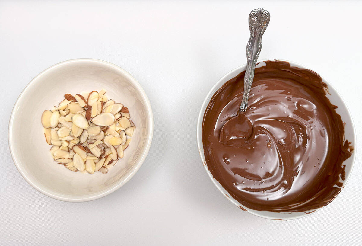 A bowl of melted chocolate and a bowl of sliced almonds. Finishing touches for the coconut macaroons.