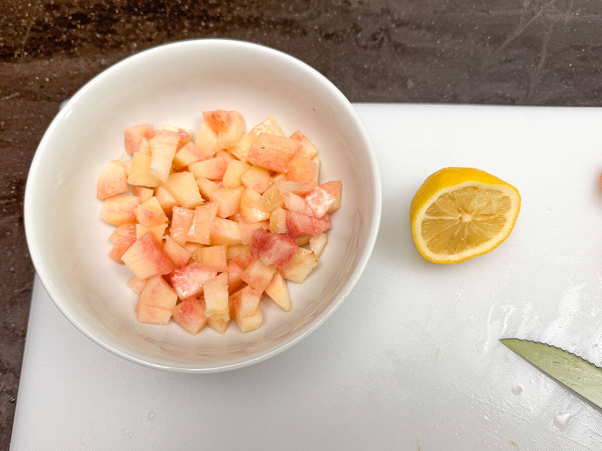 Fresh peach cut into small pieces with a squeezed lemon half to prevent browning.