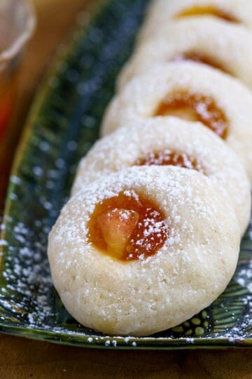 Fresh peach and preserves thumbprint cookies lined up on a narrow plate.