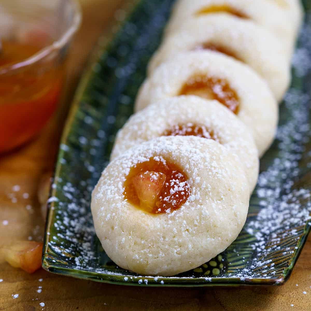 Fresh peach and preserves thumbprint cookies lined up on a narrow plate.