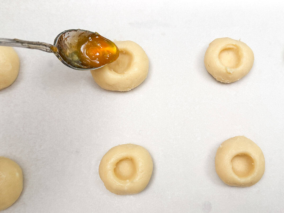 Filling an empty hole in the cookie with peach preserves.
