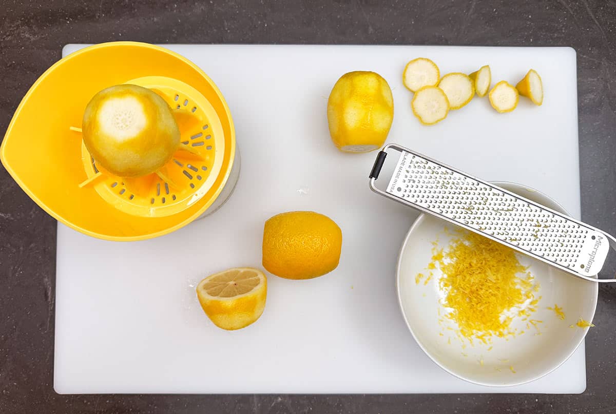Zest and juicing lemons on a cutting board.