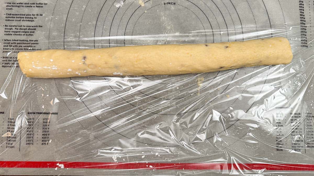 Rolling a cookie log onto plastic wrap to chill the cookie dough.