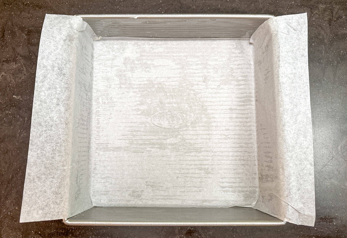 A butter pan with parchment paper across the bottom and up and over the sides.
