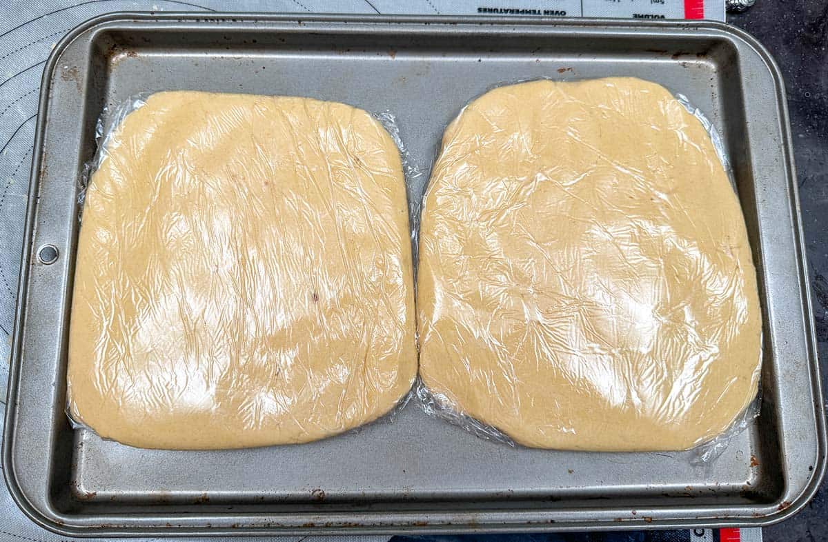 Cookie dough that has been split and flatten then wrapped in plastic wrap to be chilled.