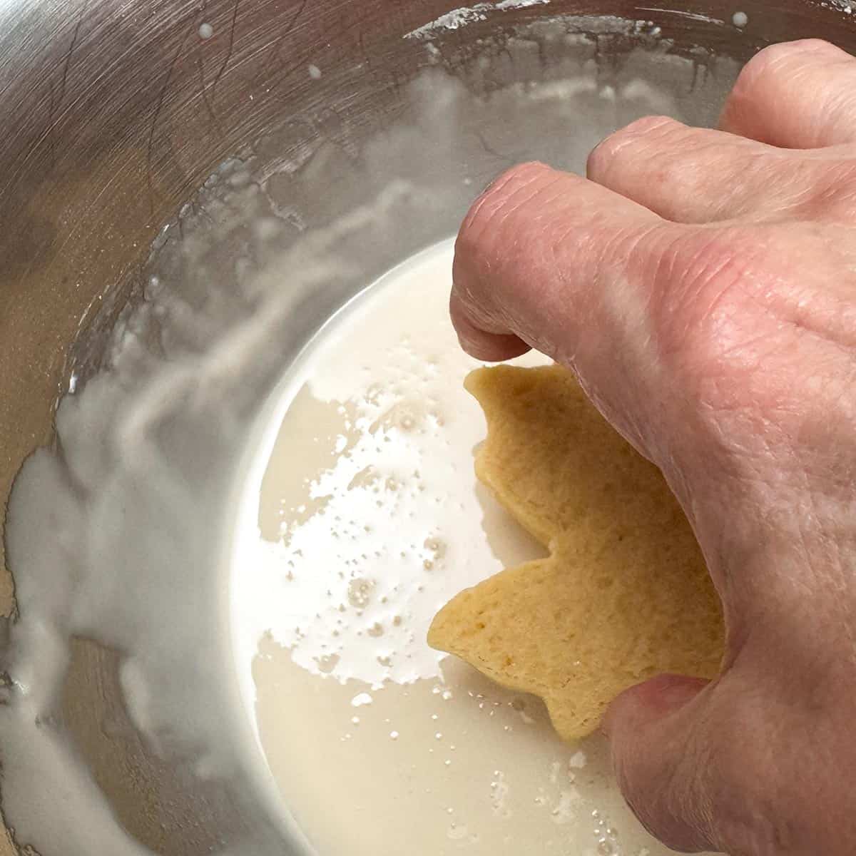 Dipping the top of a cookie in the maple glaze.
