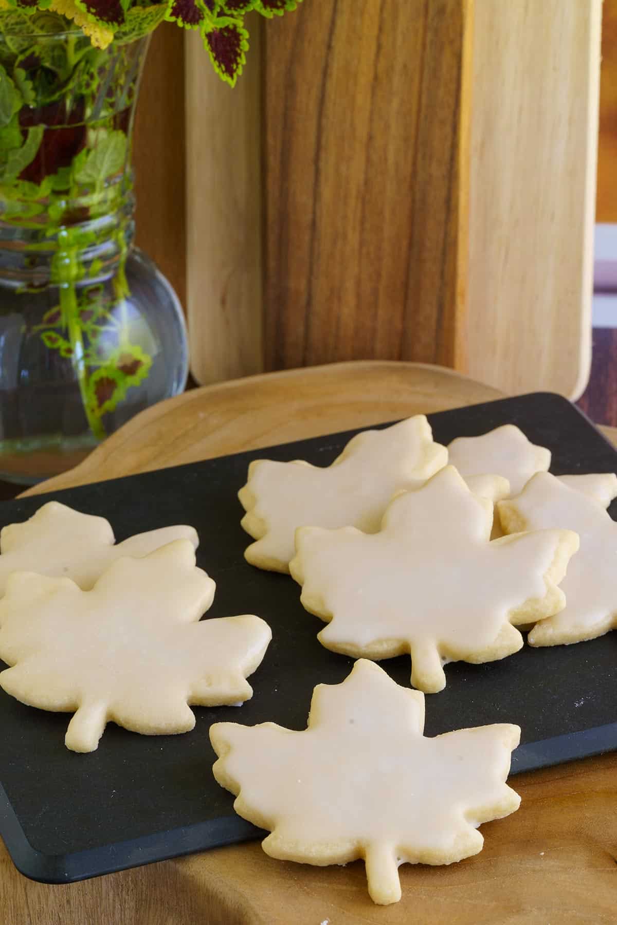 Double Maple Sugar Cookies that are leaf shaped and on a cutting board.
