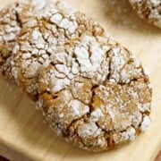 A closeup of gingerbread crinkle cookies on a wooden board.