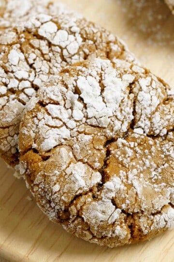 A closeup of gingerbread crinkle cookies on a wooden board.