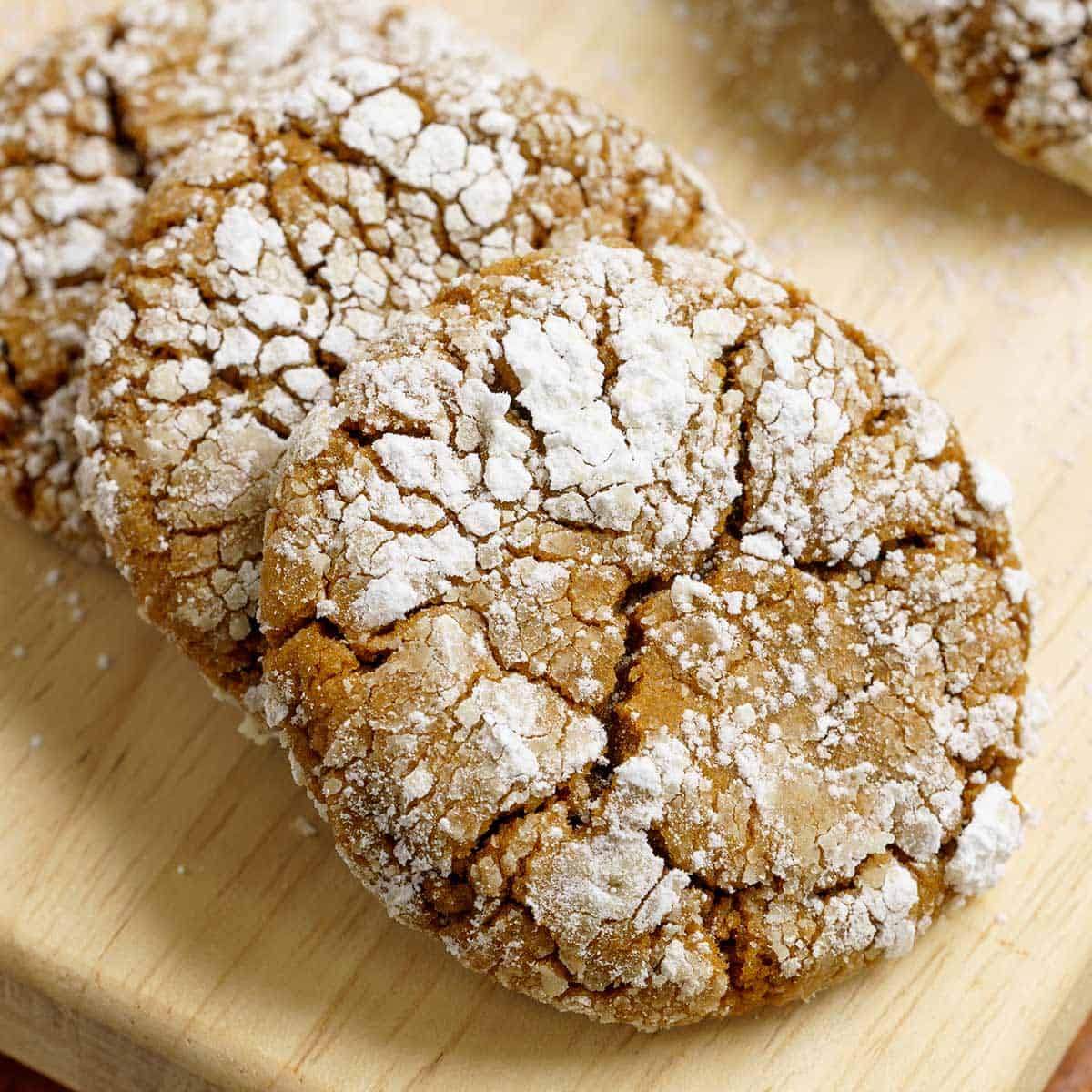 A closeup of gingerbread crinkle cookies on a wooden board.