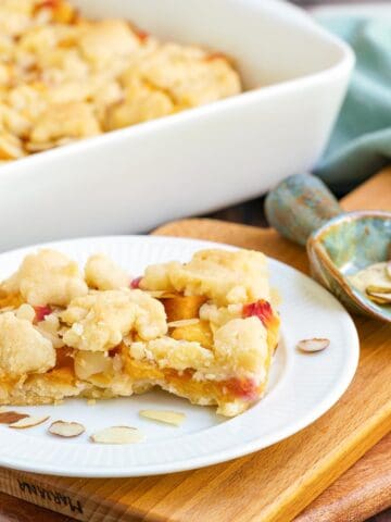 Peach almond shortbread bars on a plate with almonds slices around.