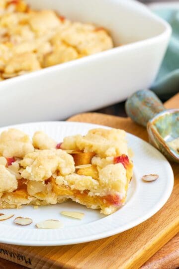 Peach almond shortbread bars on a plate with almonds slices around.