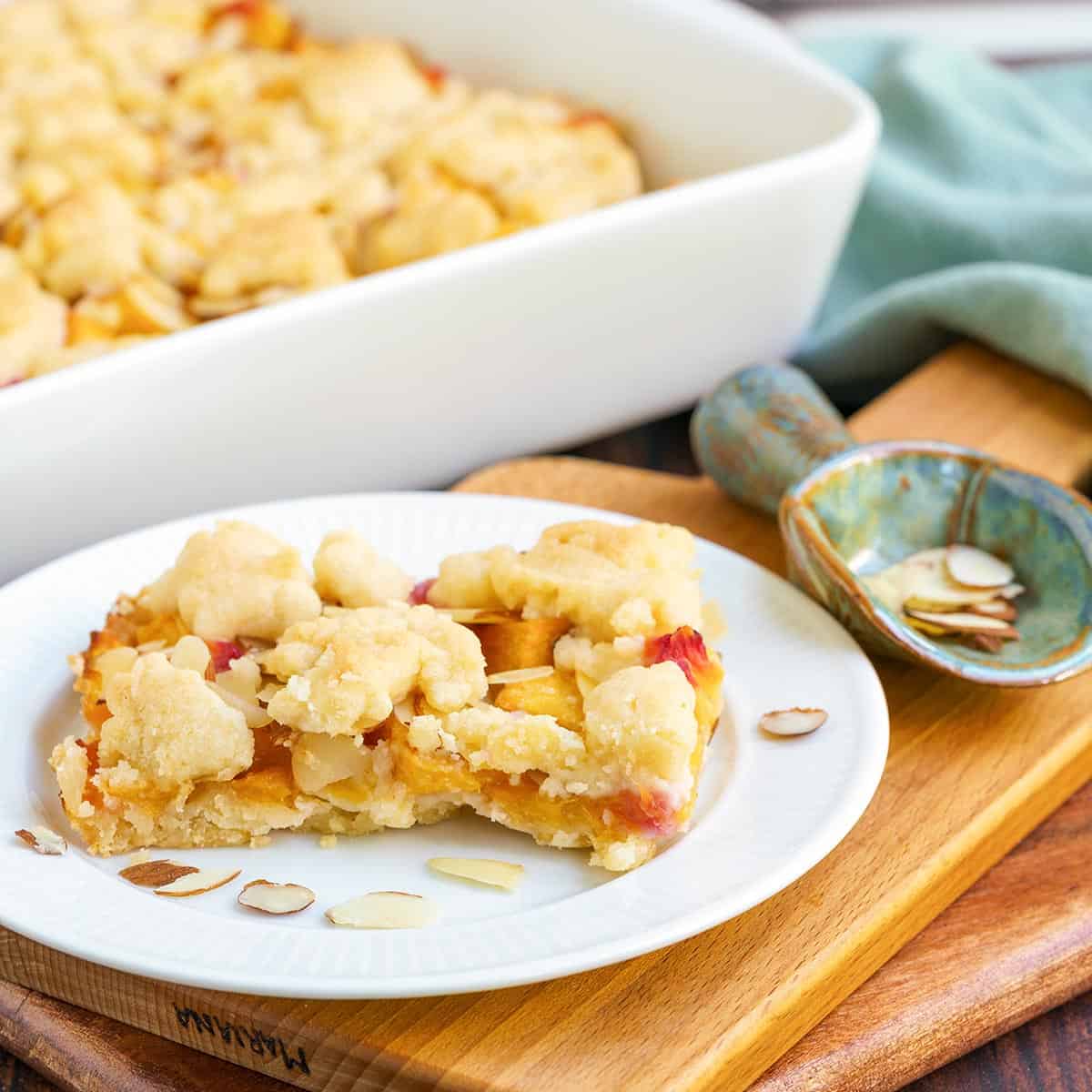 Peach almond shortbread bars on a plate with almonds slices around.