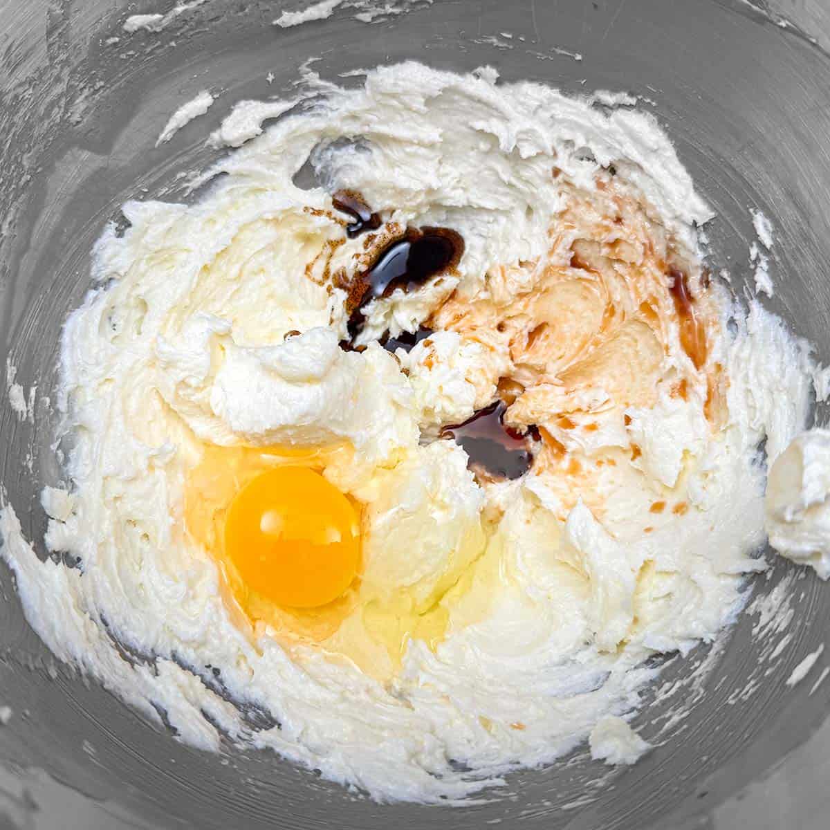 Adding an egg and both the vanilla extract and the vanilla bean paste to the cookie dough.