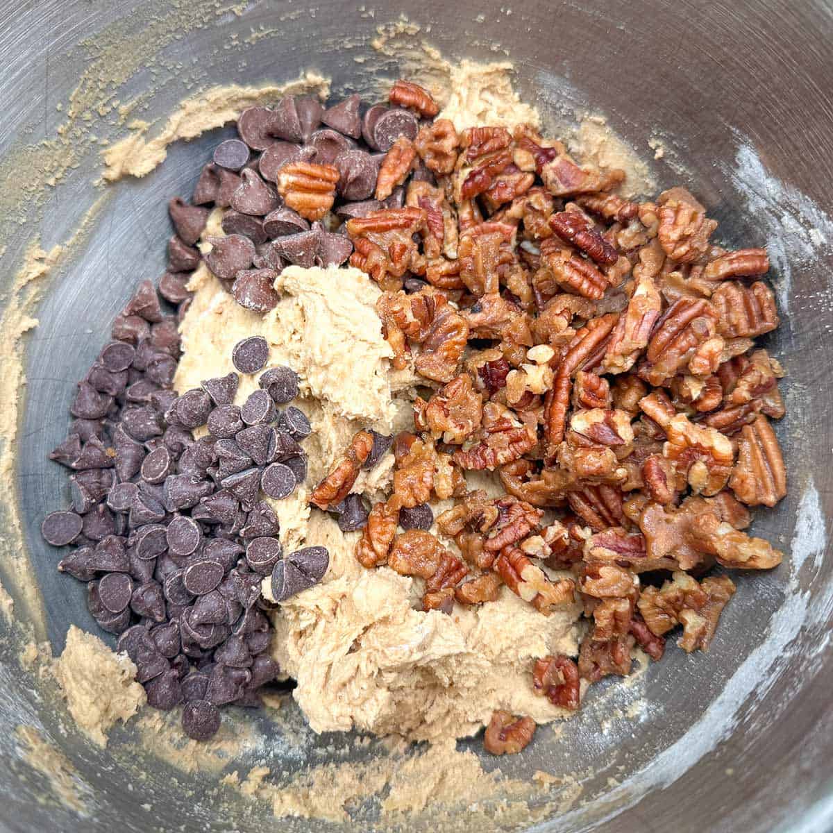 Adding the chocolate chips and glazed pecans to the cookie dough.