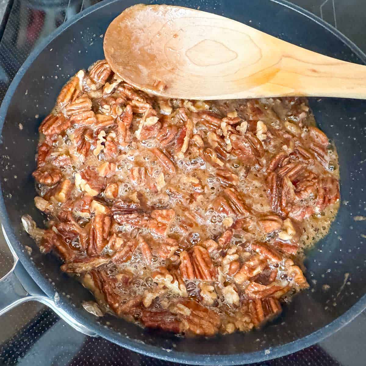 Adding the pecan pieces to the syrupy glaze to finish the reduction.