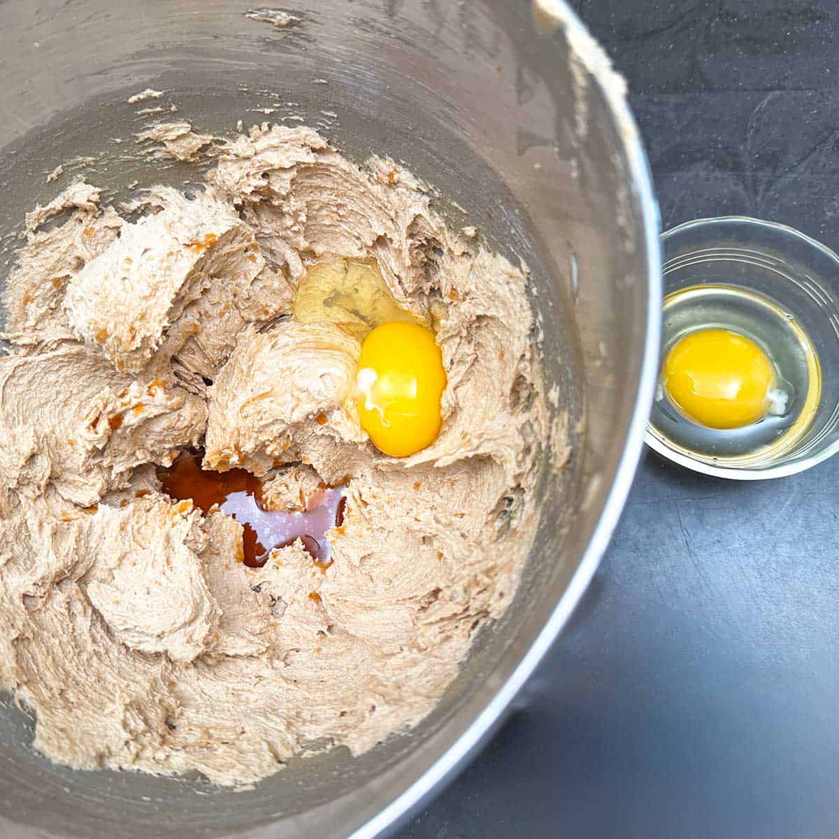 Adding the vanilla extract and the egg one at a time to the butter-sugar mixture.