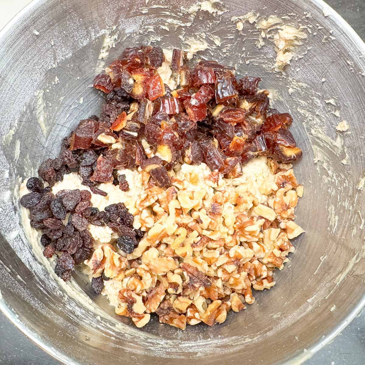 Adding walnuts, raisins, and dates to the cookie dough.