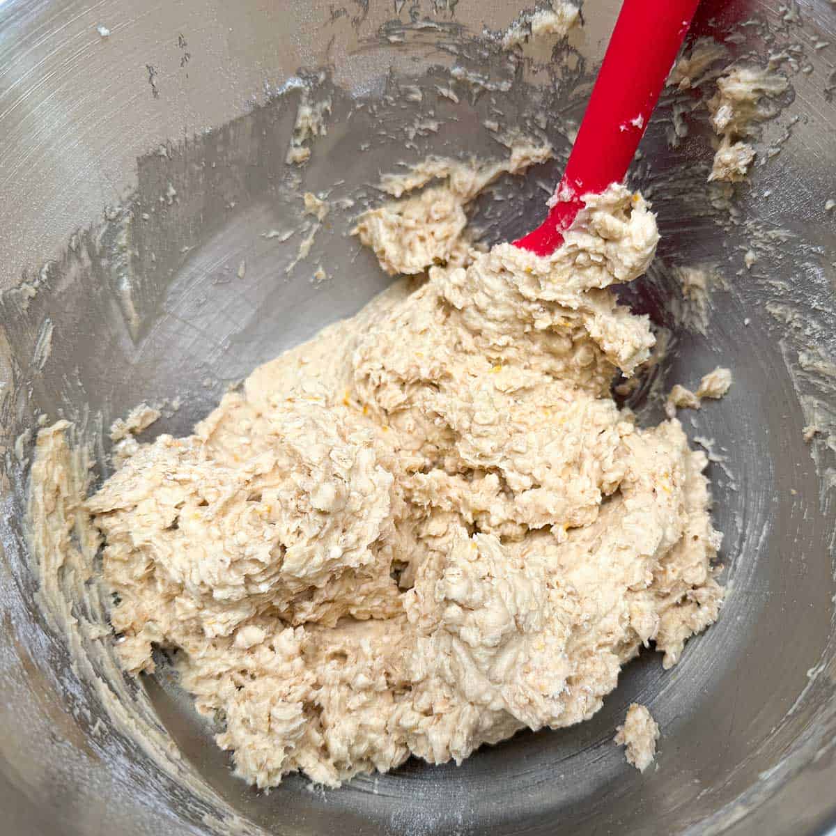 Adding the flour-oats mixture to the wet ingredients to finish the cookie dough part.