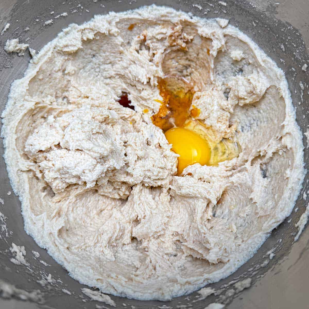 Adding the egg, orange juice and zest along with the vanilla extract to the sugar-butter mixture.