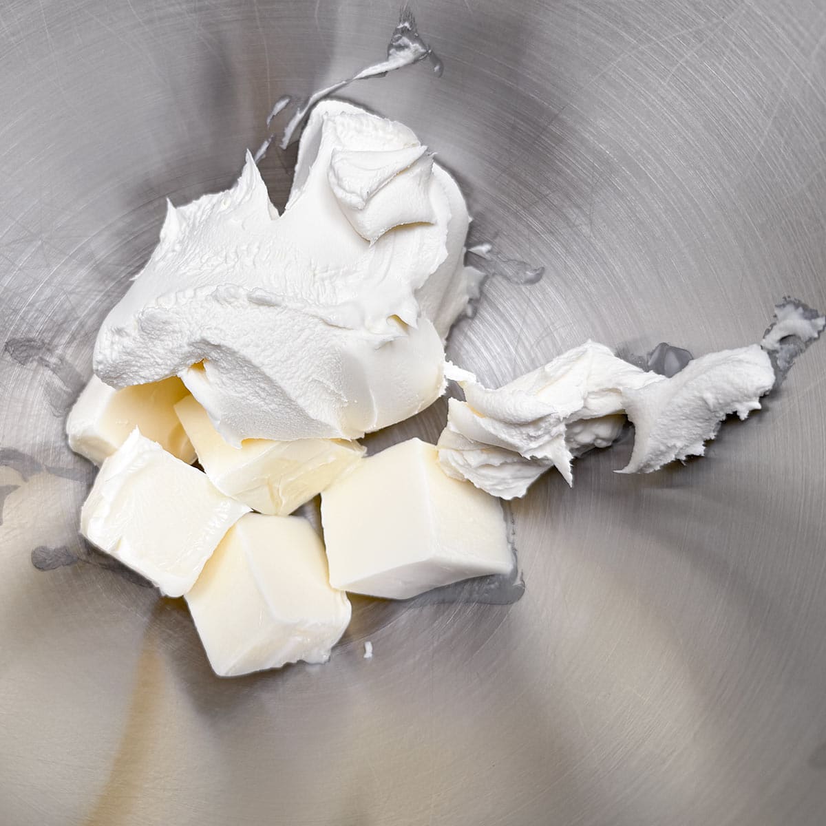 Cubed butter and the soft mascarpone in a mixer bowl ready to be combined.