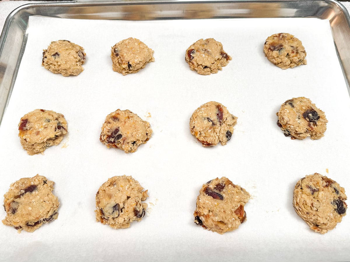 Twelve flatten cookie scooped cookie dough on parchment paper ready for the oven.
