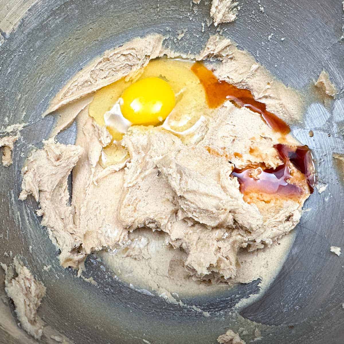 Adding the egg, vanilla extract and water to the butter-sugar mixture.