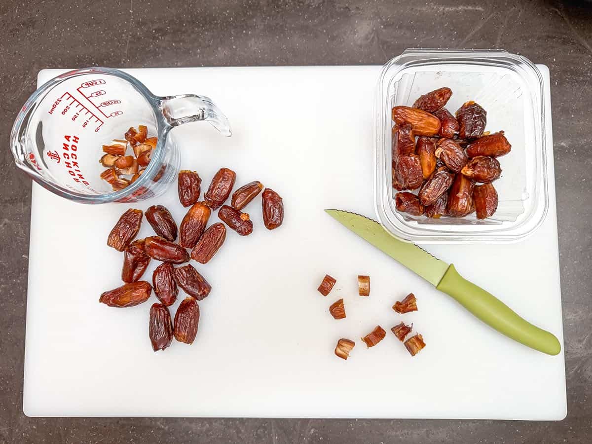 Dates on cutting board with one date cut into size pieces for the cookies.