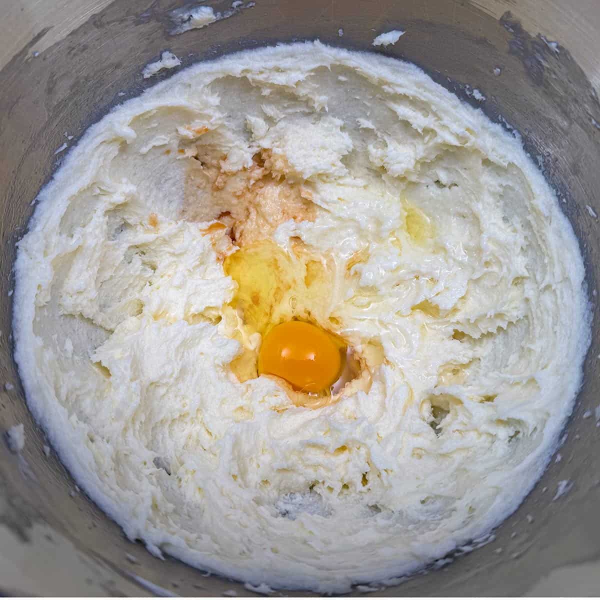 Adding egg, vanilla extract, and apple juice to the creamed butter-cream cheese mixture.