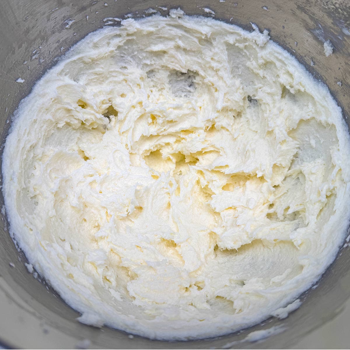 Mixing the sugar with the creamed butter-cream cheese for three minutes.