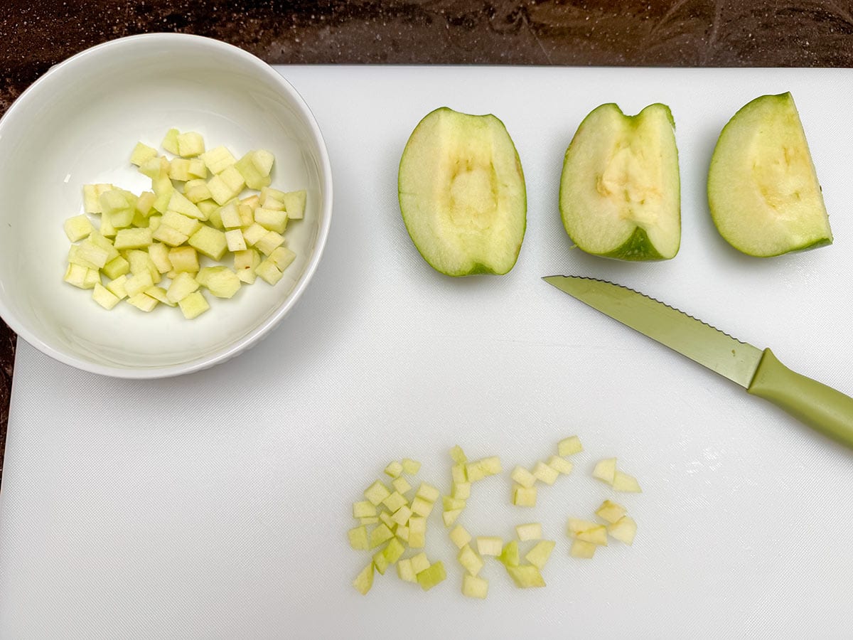 Cutting the granny smith apple sections into small pieces.