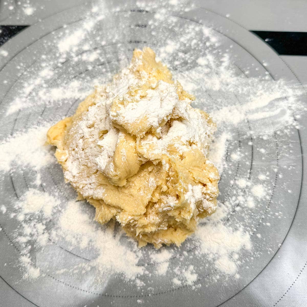 Cookie dough dumped onto a floured pasted mat.