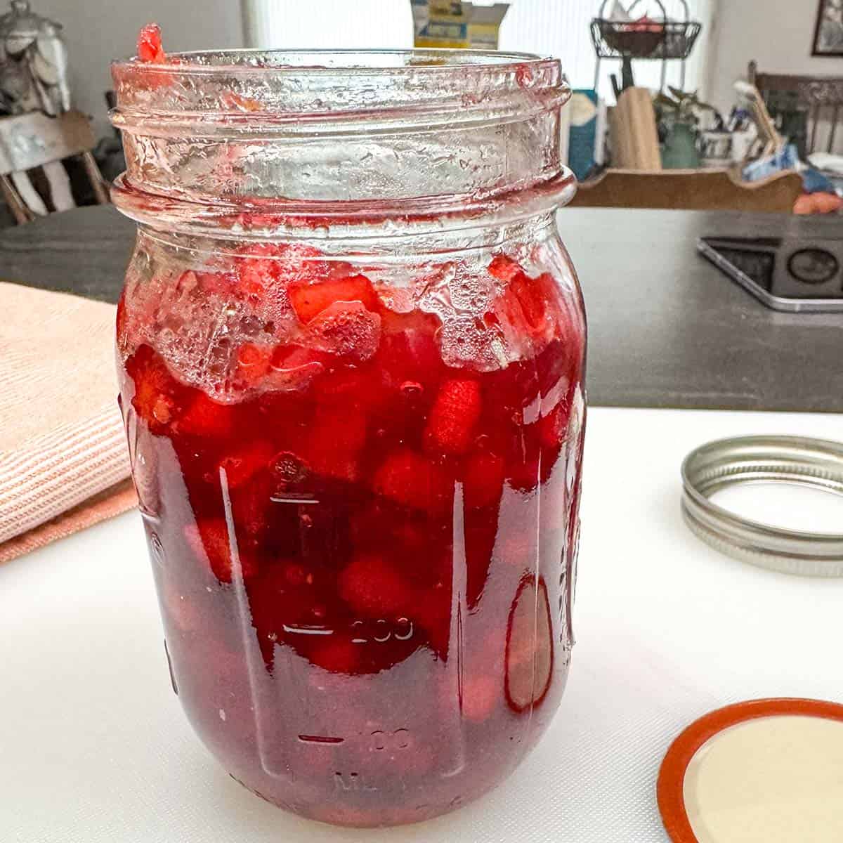 Adding the apple-cranberry jam to a glass jar so it can cool down in the fridge.