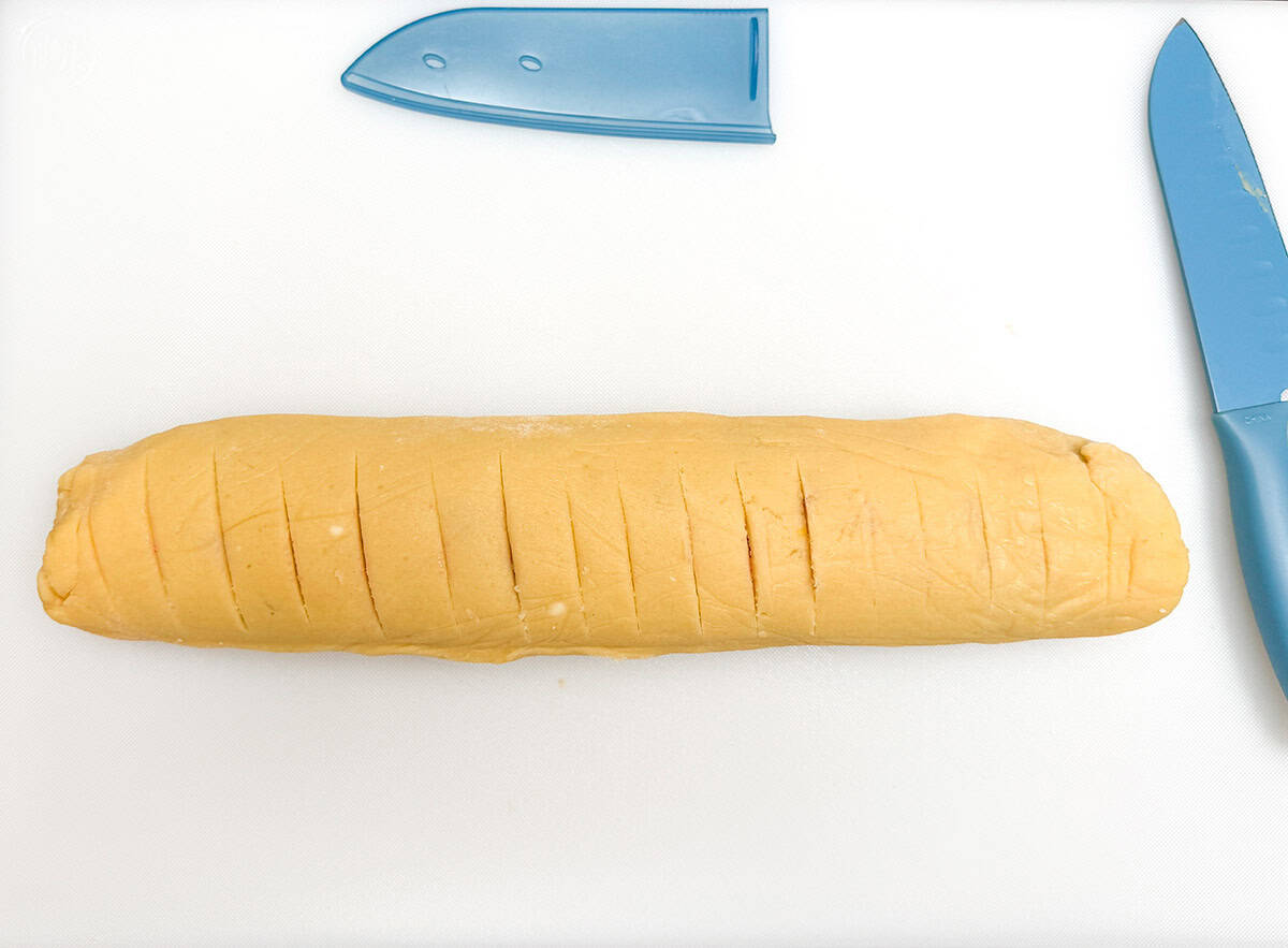 Unwrapped cookie log that has been scored at half inch marks.