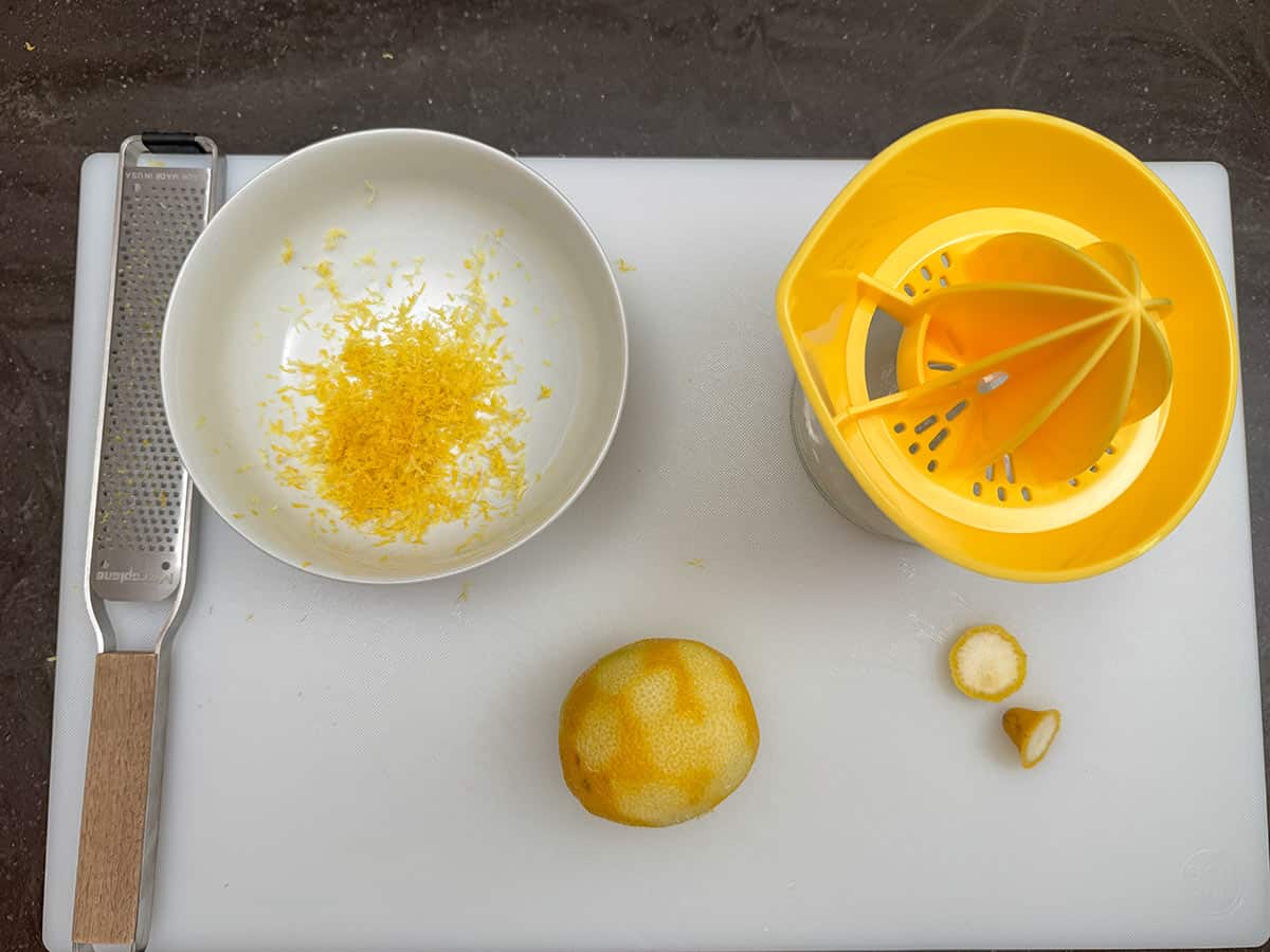 Zest and juice a lemon on a cutting board.