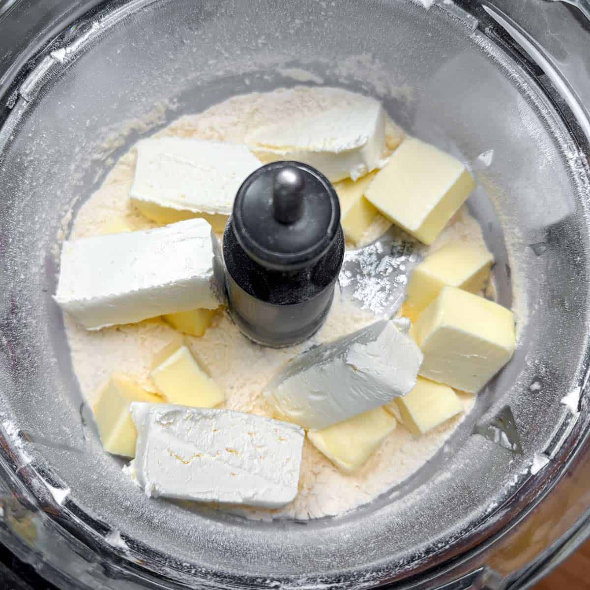 Cubed butter and cream cheese in a food processor with flour and salt.
