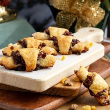 Baked cranberry orange and walnut rugelach on wooden boards.