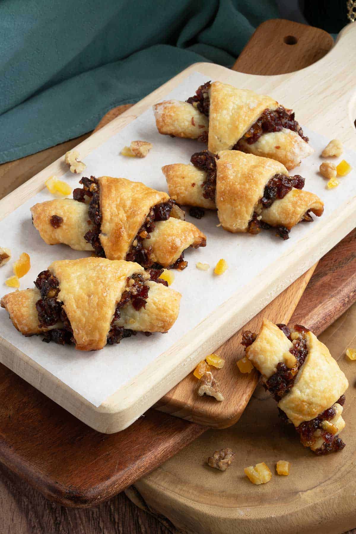 Looking down on cranberry orange and walnut rugelach cookies on wooden boards.