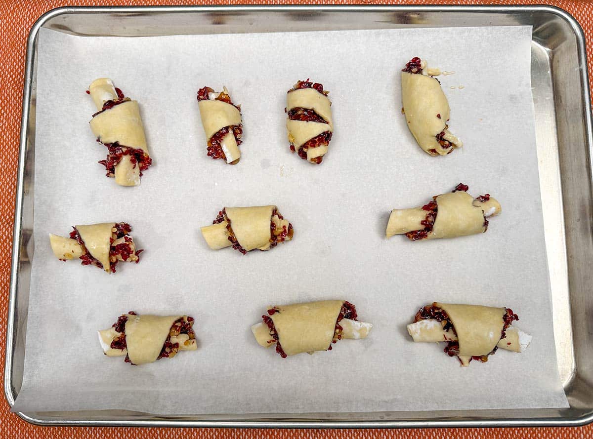 Filled and rolled rugelach's on a parchment lined cookie sheet pan.
