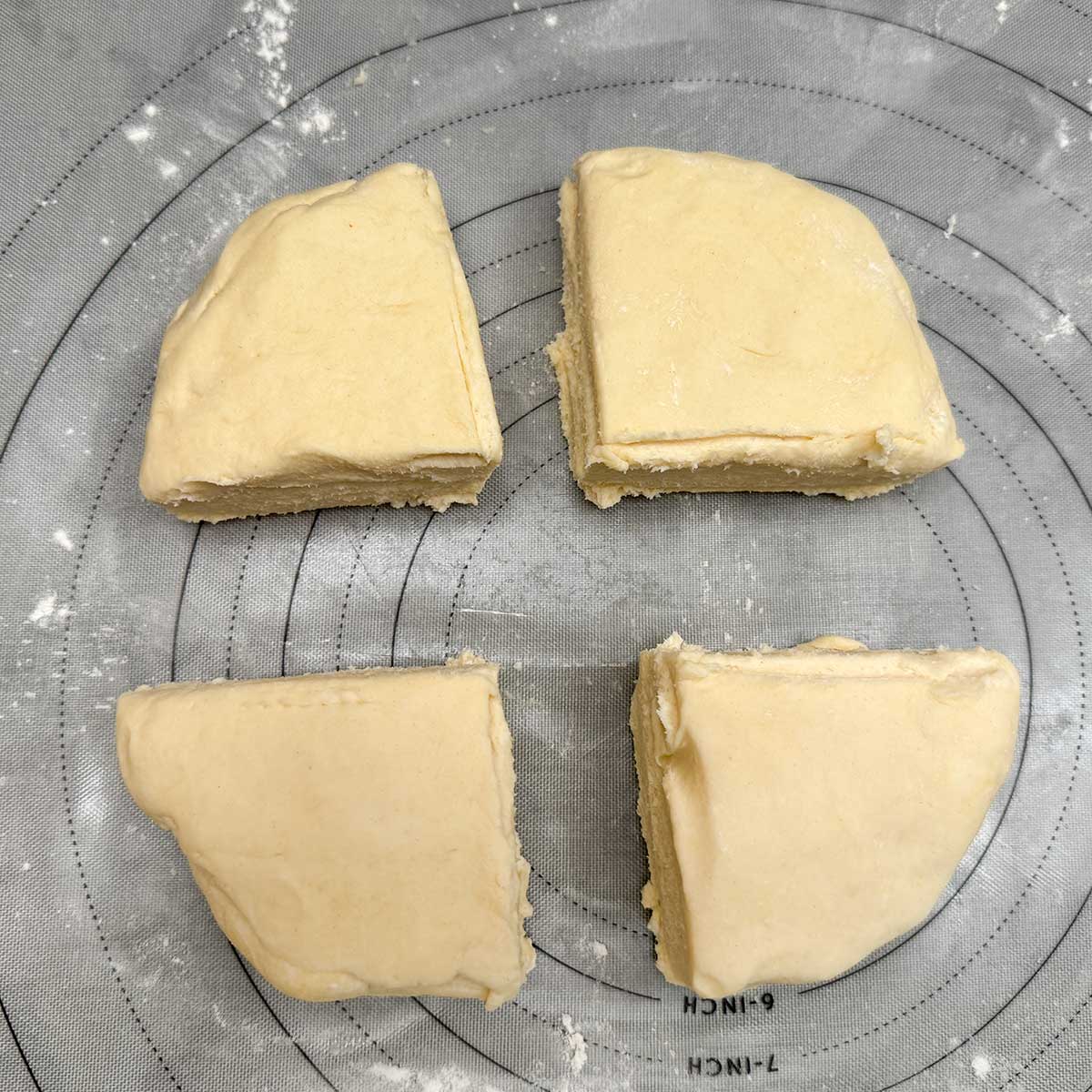 Cookie dough cut into quarters on a pastry sheet.