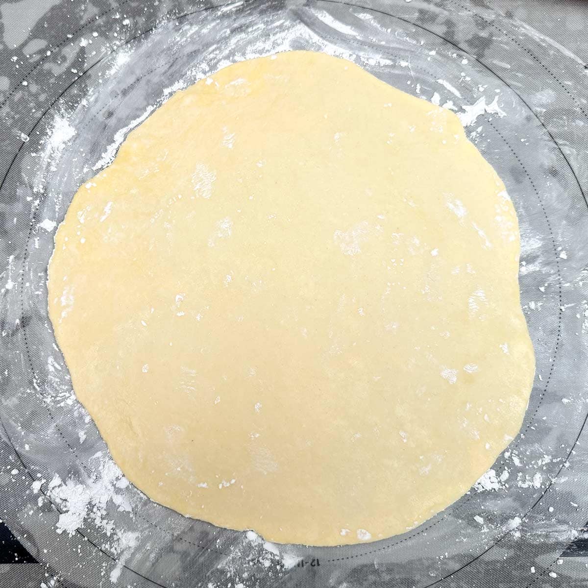 One of the quarter disks rolled out on a powdered sugar dusted pastry sheet.