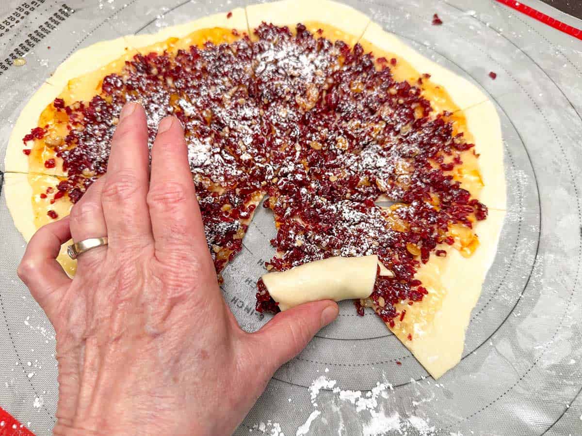 Roll the pie shaped cranberry filled triangle to place on the sheet pan for baking.