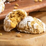 Close up of two pumpkin with applesauce and walnut cookies on a wooden board with a bite out of one.