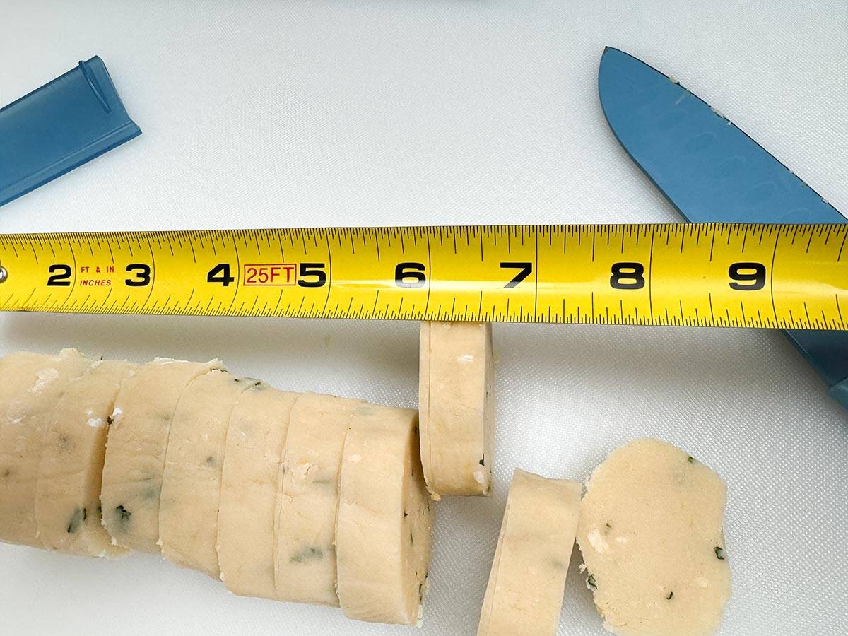 One of the eight inch log is sliced into ½" cookies to be baked.