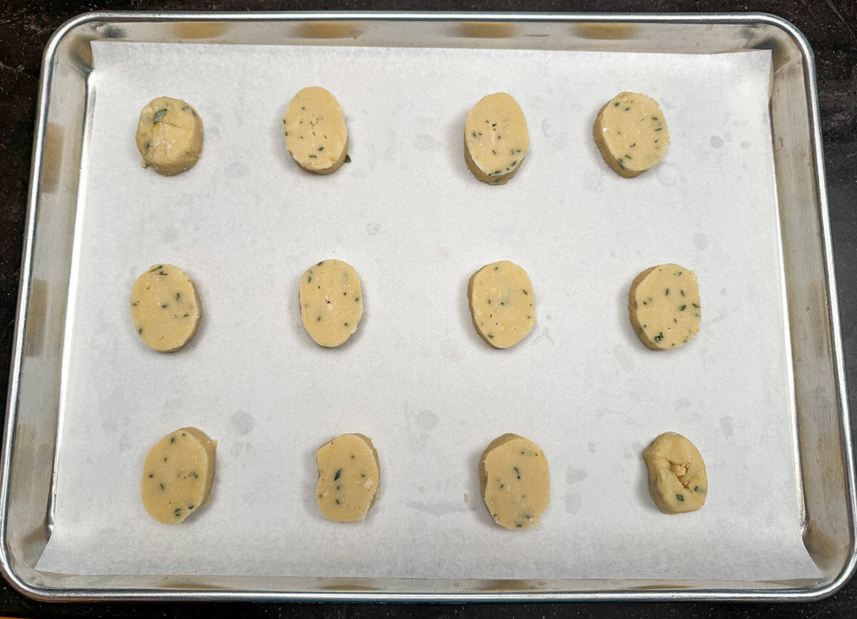 Twelve cookie slices from the one logs on the sheet pan ready for the oven.