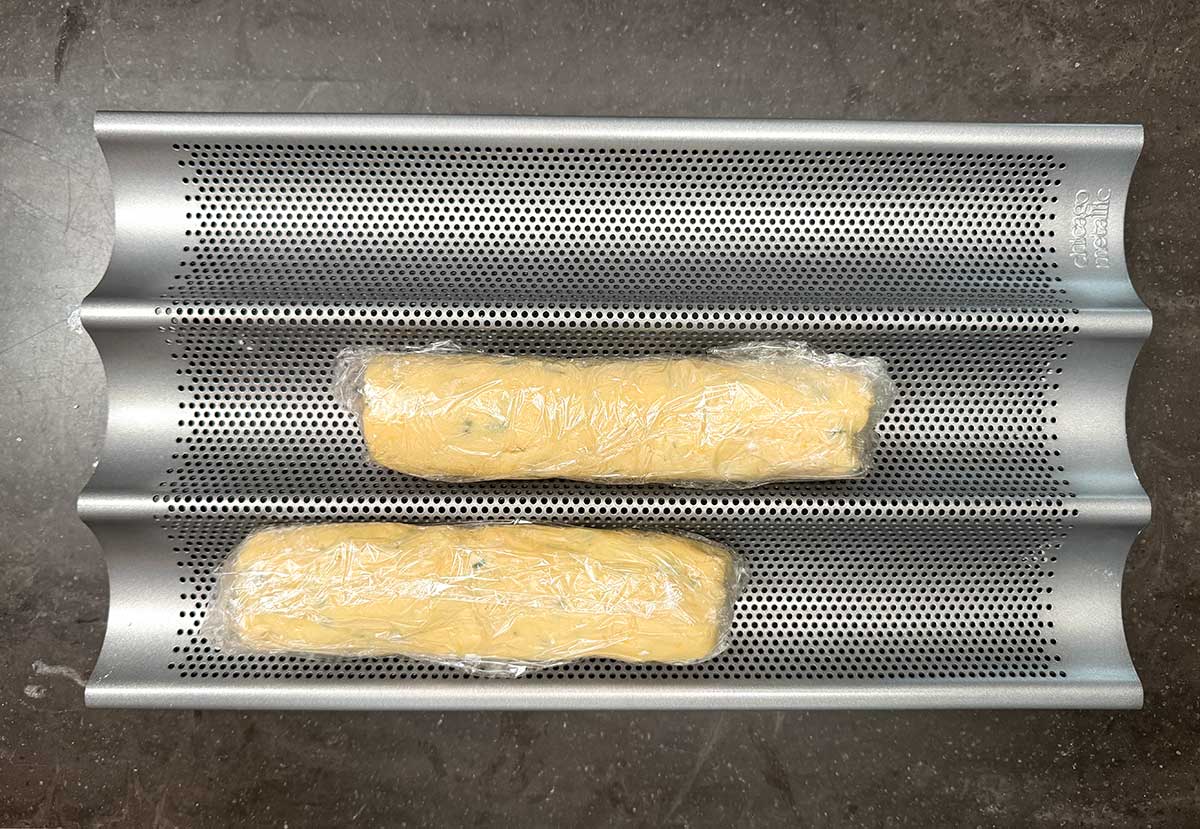 Two eight inch wrapped logs sitting a baguette pan ready for the fridge.