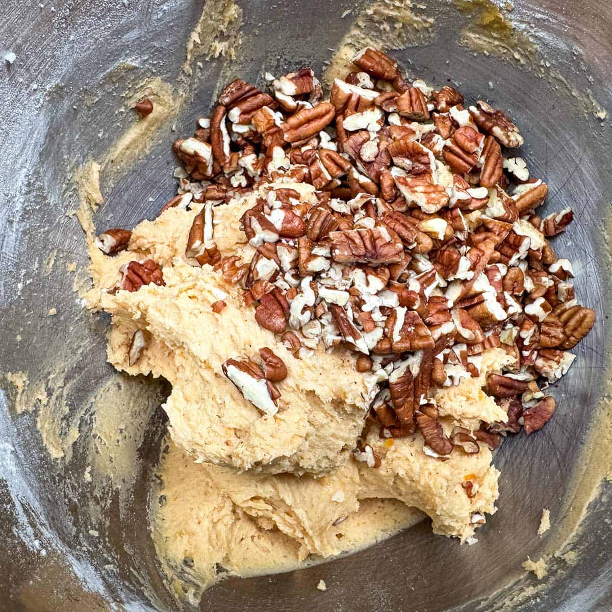 Adding the chopped pecans to the cookie dough.